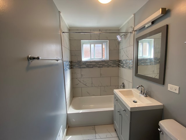 full bathroom with tiled shower / bath, vanity, and toilet