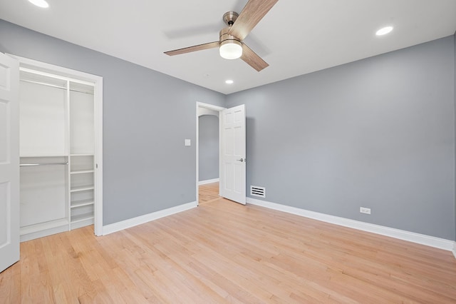 unfurnished bedroom with ceiling fan, light wood-type flooring, and a closet