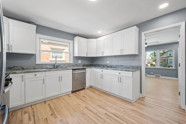 kitchen with appliances with stainless steel finishes, a healthy amount of sunlight, sink, and white cabinets