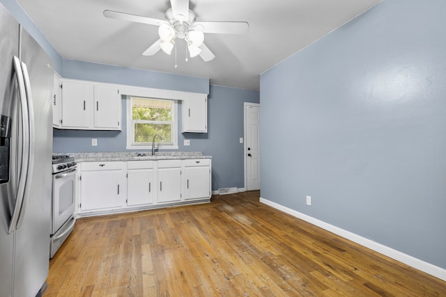 kitchen with white cabinets, ceiling fan, stainless steel appliances, and light hardwood / wood-style flooring