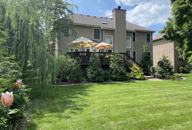 rear view of house with a lawn and a wooden deck