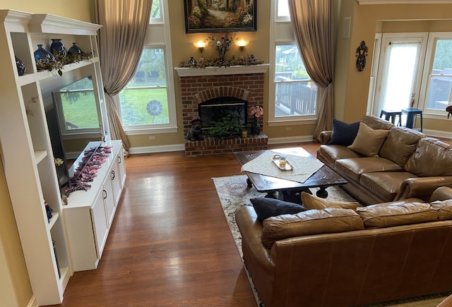 living room with hardwood / wood-style flooring, a brick fireplace, and a healthy amount of sunlight