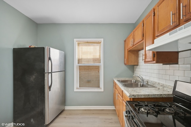 kitchen with decorative backsplash, light hardwood / wood-style flooring, appliances with stainless steel finishes, and sink