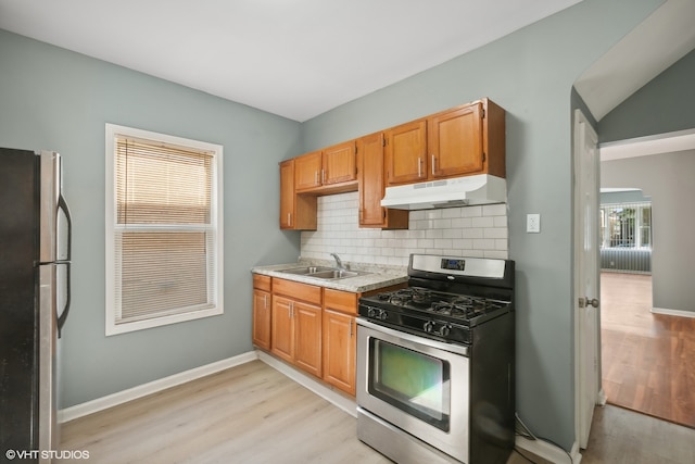 kitchen with backsplash, appliances with stainless steel finishes, sink, and light wood-type flooring