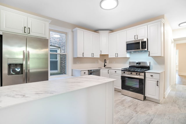 kitchen featuring light hardwood / wood-style flooring, appliances with stainless steel finishes, sink, and white cabinetry