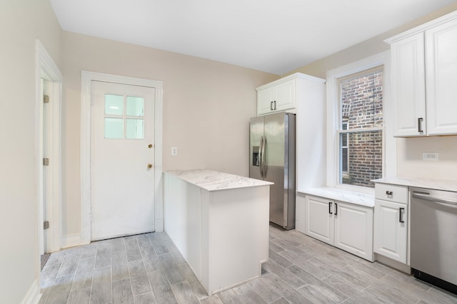 kitchen featuring light wood-type flooring, white cabinetry, stainless steel appliances, and light stone counters