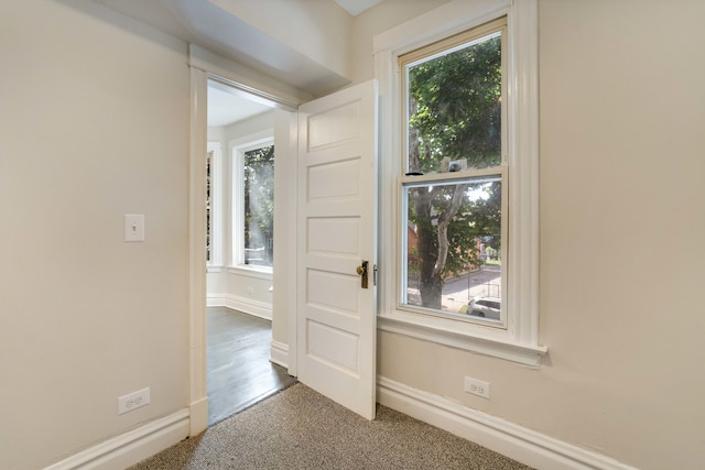 interior space featuring a healthy amount of sunlight and dark colored carpet