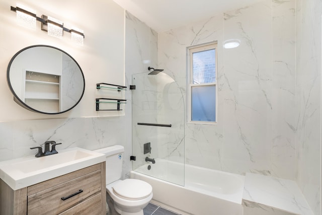 full bathroom with tile walls, tiled shower / bath, vanity, and toilet