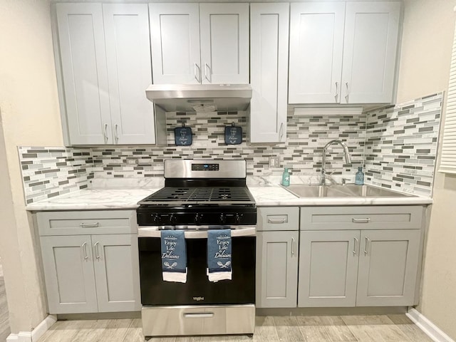 4764 S Shields Ave, Chicago, IL 60609 - kitchen featuring stainless steel range with gas stovetop, under cabinet range hood, tasteful backsplash, and light wood finished floors
