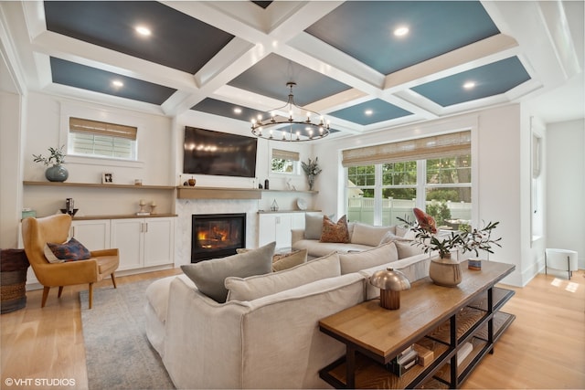 living room featuring beam ceiling, coffered ceiling, an inviting chandelier, and light hardwood / wood-style flooring