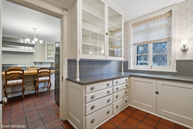 kitchen with ventilation hood, decorative light fixtures, and white cabinets