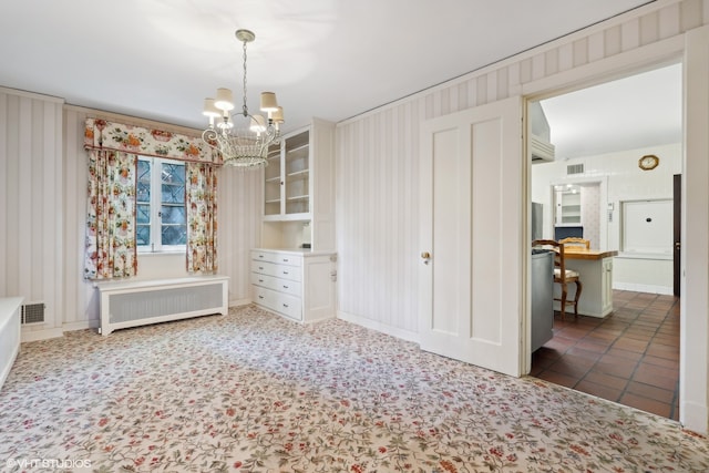 unfurnished bedroom featuring radiator heating unit, a notable chandelier, crown molding, and dark tile patterned floors