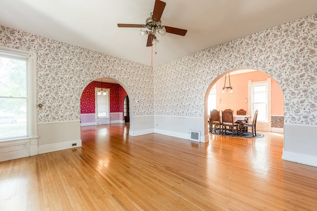 empty room with wood-type flooring, ceiling fan, and plenty of natural light