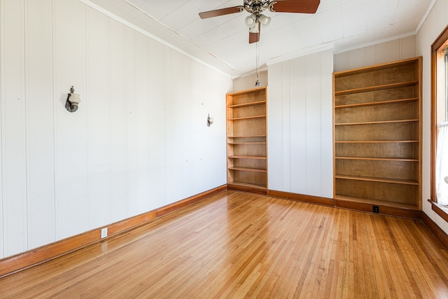 unfurnished room featuring crown molding, wood walls, ceiling fan, and hardwood / wood-style flooring