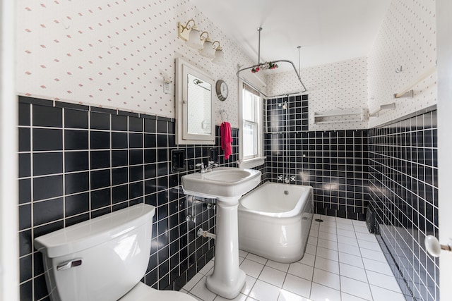 bathroom featuring tile walls, tile patterned flooring, a washtub, and toilet