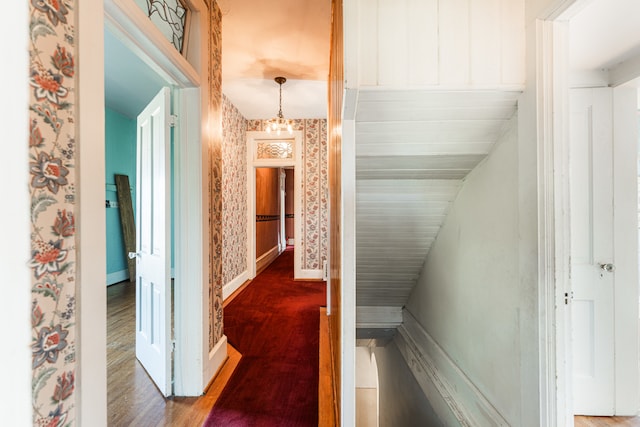 corridor featuring hardwood / wood-style flooring, lofted ceiling, and a chandelier