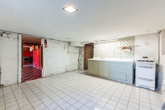 kitchen with light tile patterned floors, heating unit, sink, and white gas range