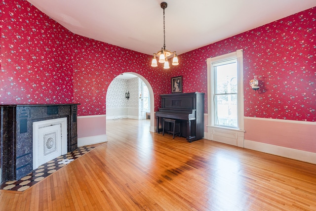 unfurnished living room with wood-type flooring, vaulted ceiling, and a chandelier