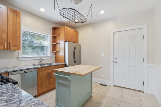 kitchen featuring wooden counters, a kitchen island, sink, appliances with stainless steel finishes, and light tile patterned floors