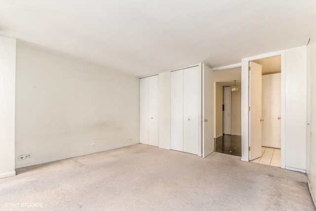 unfurnished bedroom featuring light carpet and ensuite bathroom