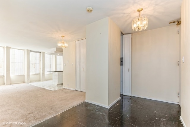 unfurnished room featuring a notable chandelier and dark colored carpet