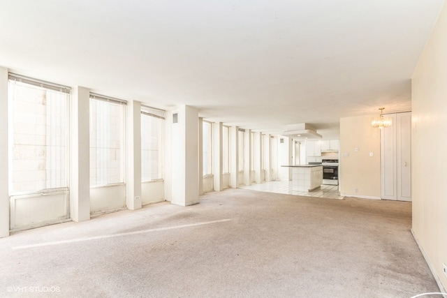 unfurnished living room with light carpet and a chandelier