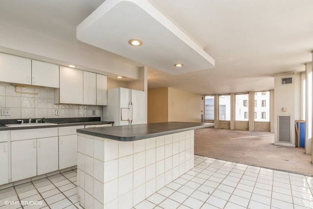 kitchen featuring white cabinetry, a center island, white refrigerator with ice dispenser, and light colored carpet