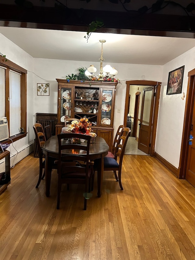 dining room with light hardwood / wood-style floors, a baseboard heating unit, and a chandelier