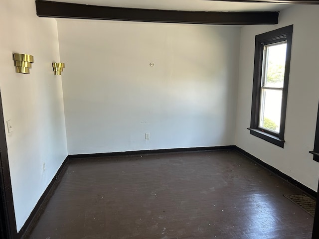 empty room with beam ceiling, dark hardwood / wood-style floors, and a wealth of natural light