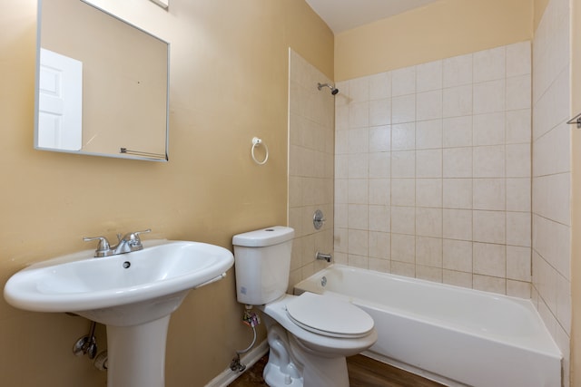 bathroom with hardwood / wood-style floors, tiled shower / bath, and toilet