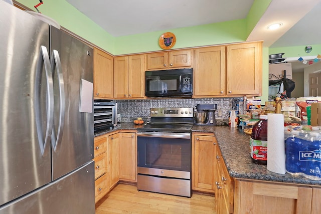 kitchen with stainless steel appliances, dark stone counters, light wood-type flooring, and backsplash