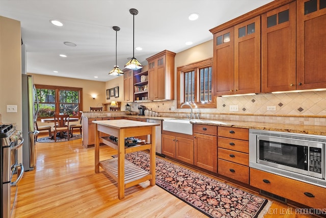 kitchen featuring appliances with stainless steel finishes, light wood-type flooring, sink, and decorative light fixtures