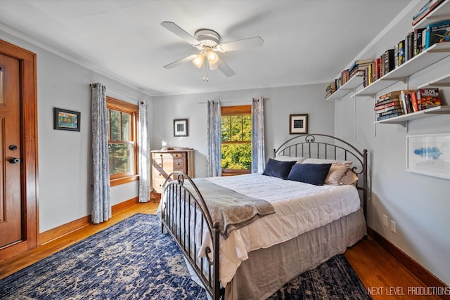 bedroom featuring multiple windows, ornamental molding, light wood-type flooring, and ceiling fan