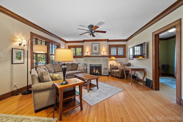 living room featuring crown molding, light hardwood / wood-style floors, a fireplace, and ceiling fan