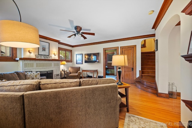 living room featuring ornamental molding, a brick fireplace, ceiling fan, and hardwood / wood-style flooring