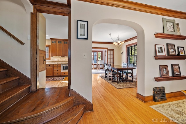 interior space featuring an inviting chandelier, crown molding, and light hardwood / wood-style floors