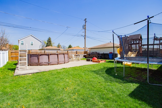 view of yard with a trampoline, a covered pool, and a patio