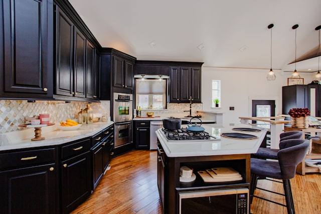 kitchen featuring decorative light fixtures, light hardwood / wood-style floors, tasteful backsplash, and stainless steel appliances