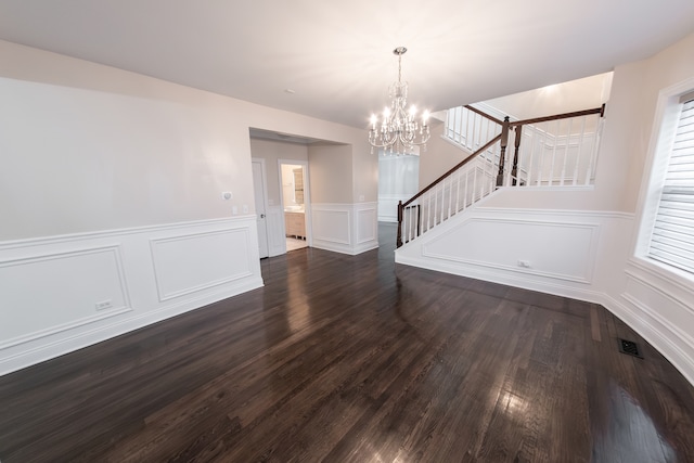 empty room with a chandelier and dark hardwood / wood-style floors