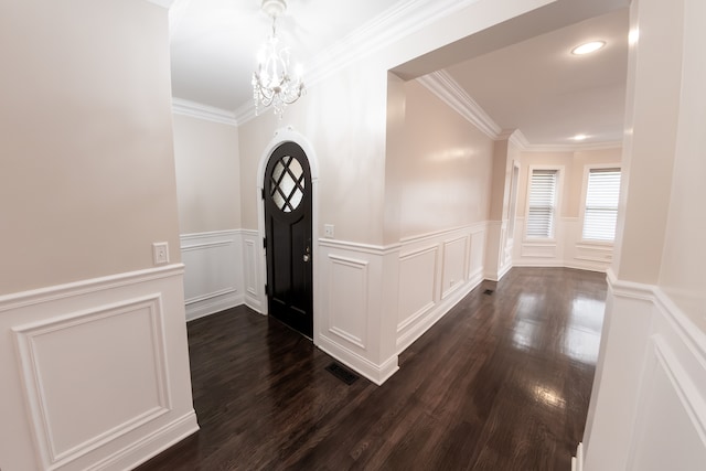 entrance foyer featuring ornamental molding, a notable chandelier, and dark hardwood / wood-style floors