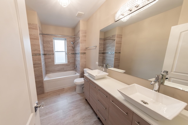 full bathroom featuring toilet, tiled shower / bath, and vanity