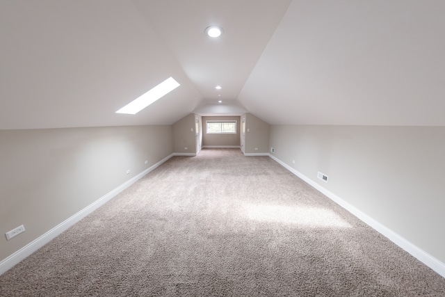 additional living space featuring lofted ceiling with skylight and carpet