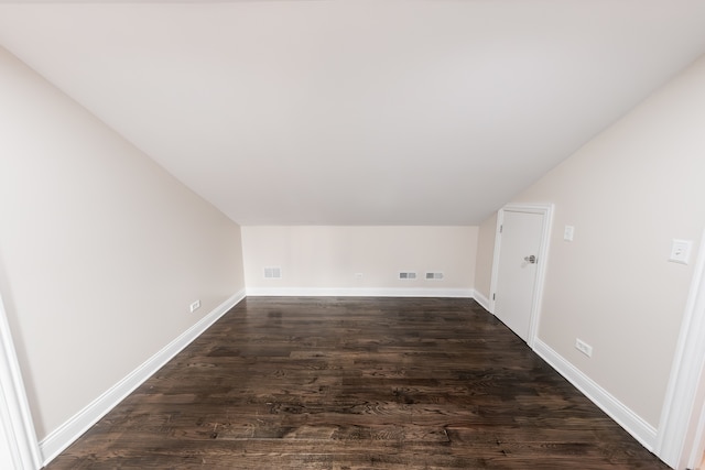 additional living space featuring dark wood-type flooring and vaulted ceiling