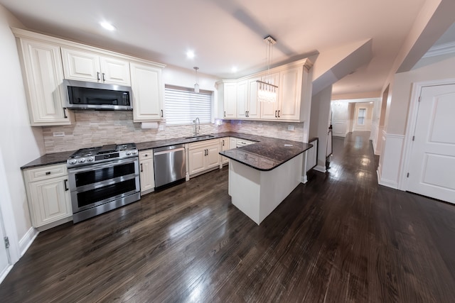 kitchen featuring dark hardwood / wood-style floors, hanging light fixtures, stainless steel appliances, sink, and white cabinets