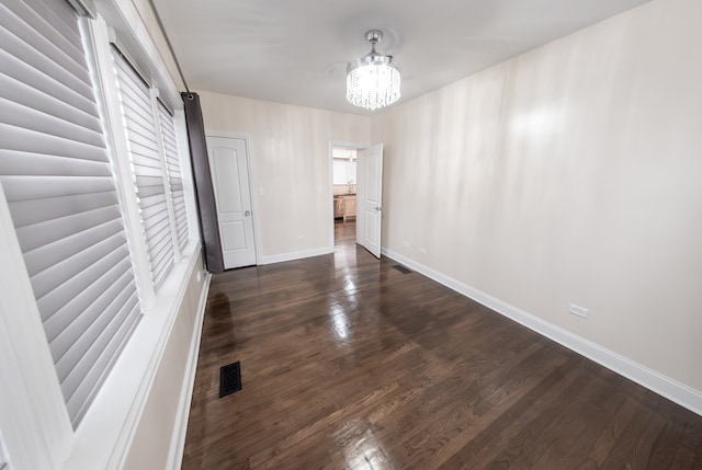 empty room with dark hardwood / wood-style flooring and a chandelier