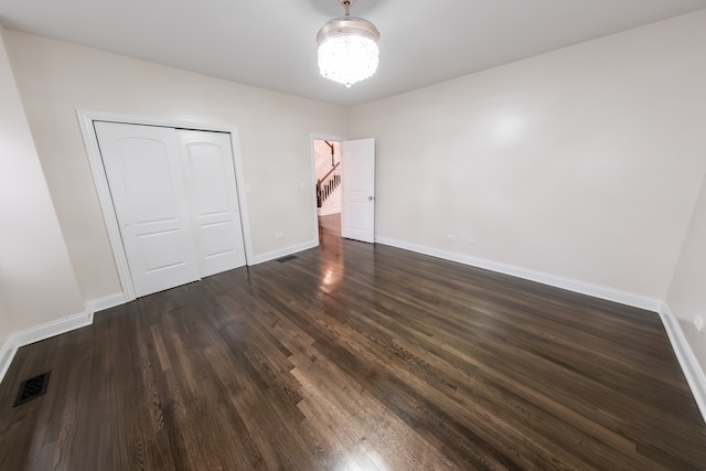 unfurnished bedroom with a closet and dark hardwood / wood-style flooring