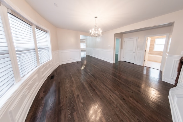 unfurnished dining area featuring a chandelier and dark hardwood / wood-style floors