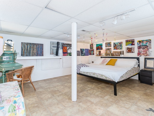 bedroom with a drop ceiling and track lighting