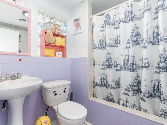 bathroom with tile walls, sink, curtained shower, and toilet