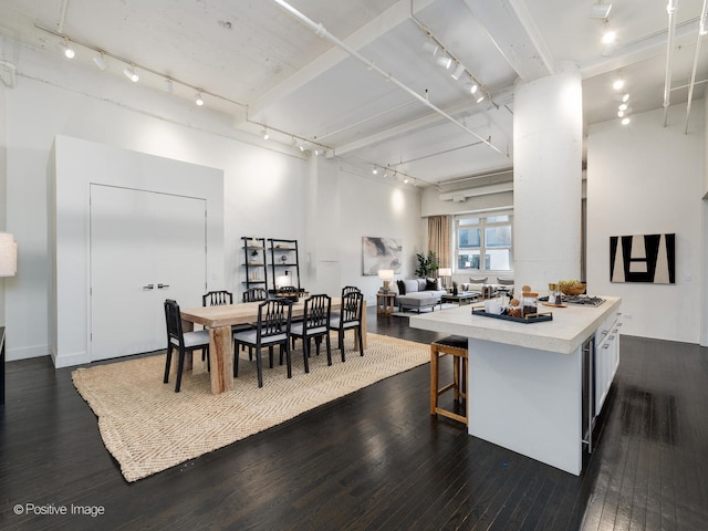 kitchen with white cabinetry, a breakfast bar, a kitchen island, dark hardwood / wood-style flooring, and track lighting